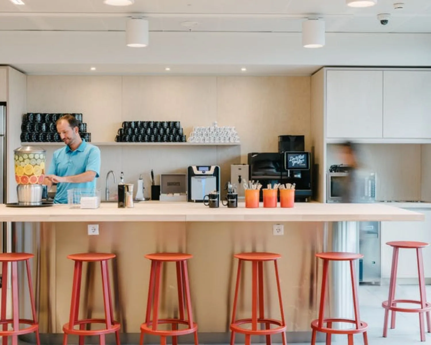 Moderne pantry met rode barkrukken en een drankstation in kantoorruimte aan de Strawinskylaan 4117.