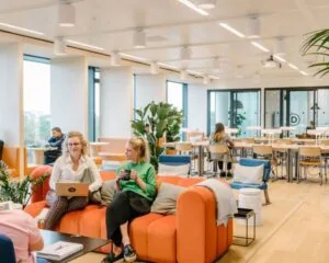 Moderne gezamenlijke kantoorruimte aan de Strawinskylaan 4117 met kleurrijke zithoek en werkplekken.