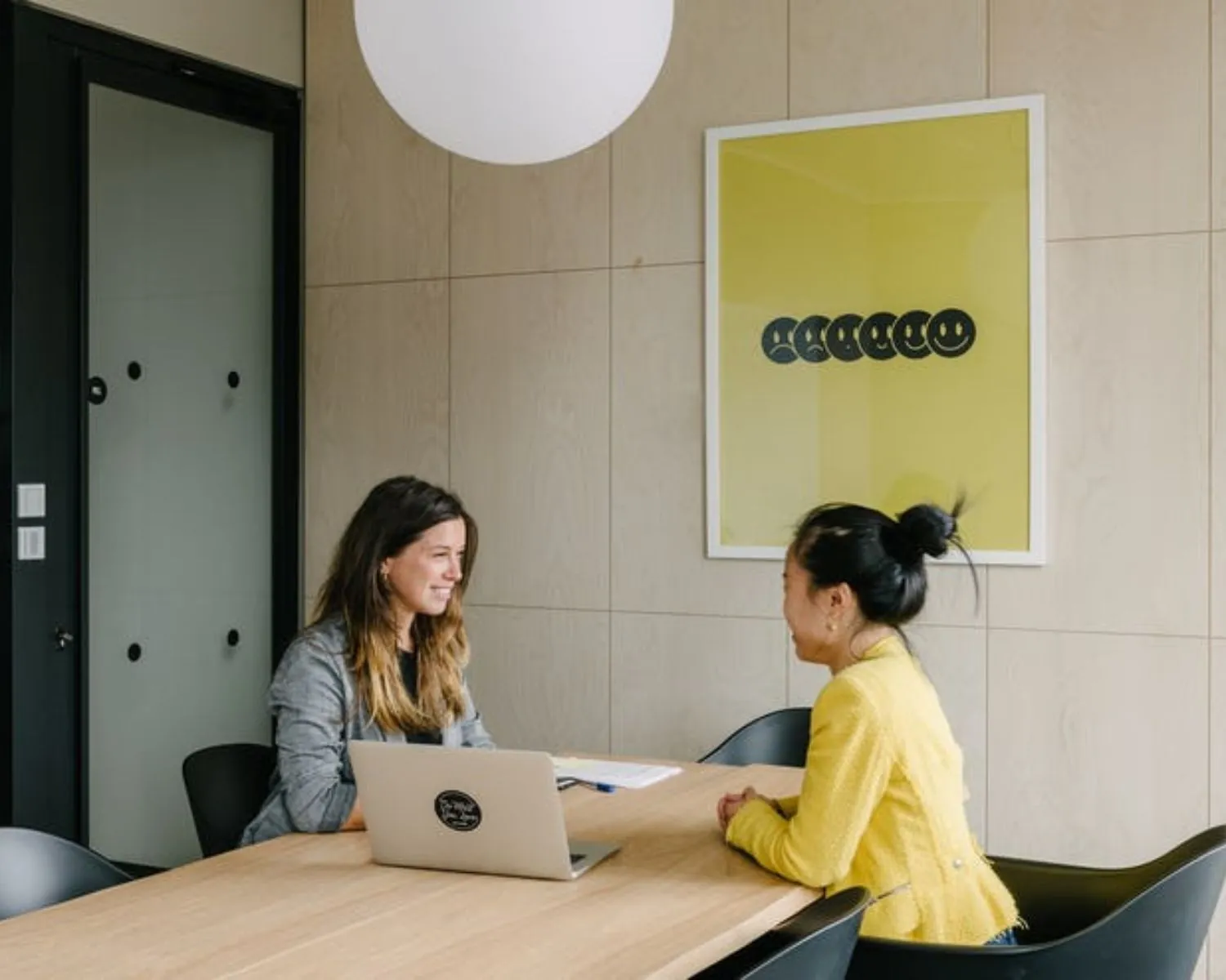 Twee vrouwen in gesprek aan een vergadertafel in een moderne kantoorruimte aan de Strawinskylaan.