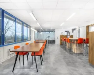 Moderne kantoorruimte in Tiel met grote ramen, oranje stoelen en ruime werktafels aan de Laan van Westroijen 6.
