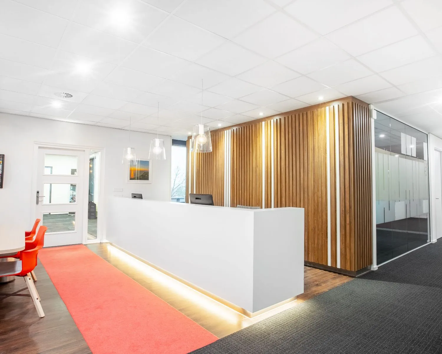 Moderne kantoorruimte met witte receptiebalie, houten wandpanelen en glazen vergaderruimtes aan de Laan van Westroijen 6 in Tiel.