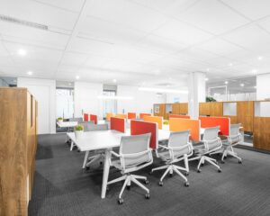 Moderne kantoorruimte in Tiel met flexwerkplekken, oranje scheidingspanelen en houten kasten.