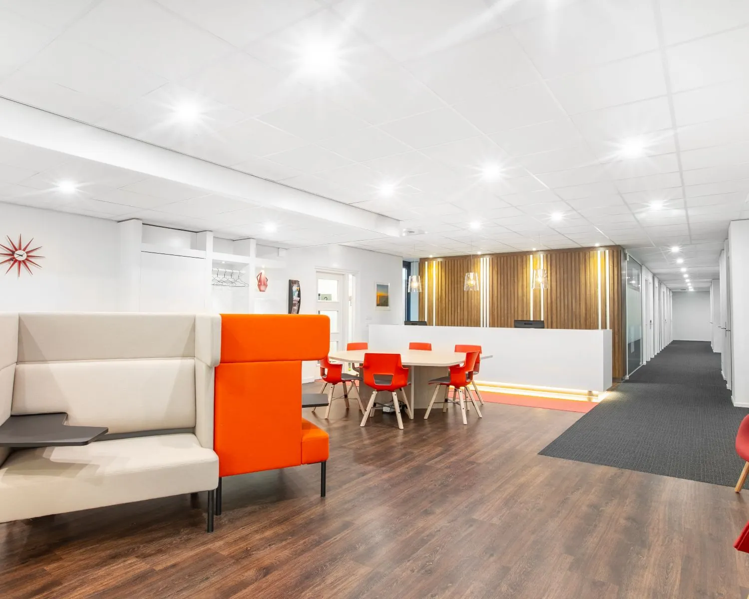 Moderne kantoorruimte aan de Laan van Westroijen 6 in Tiel met kleurrijke meubels, houten vloer en een ontvangstbalie.