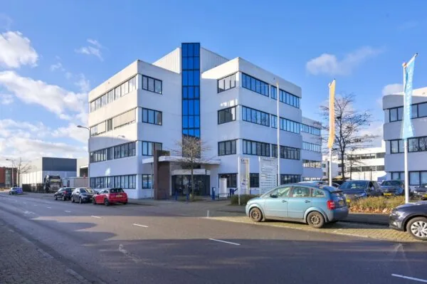 Modern wit kantoorgebouw aan de Kobaltweg 11 met parkeergelegenheid en vlaggenmasten, gezien vanaf de straat.