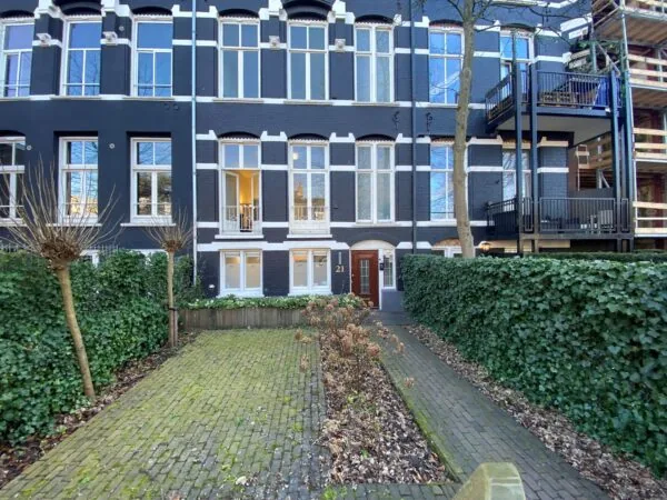 Vooraanzicht van een kantoorpand aan de Sophialaan 21 in Amsterdam met een betegelde voortuin en donkere gevel met witte accenten.