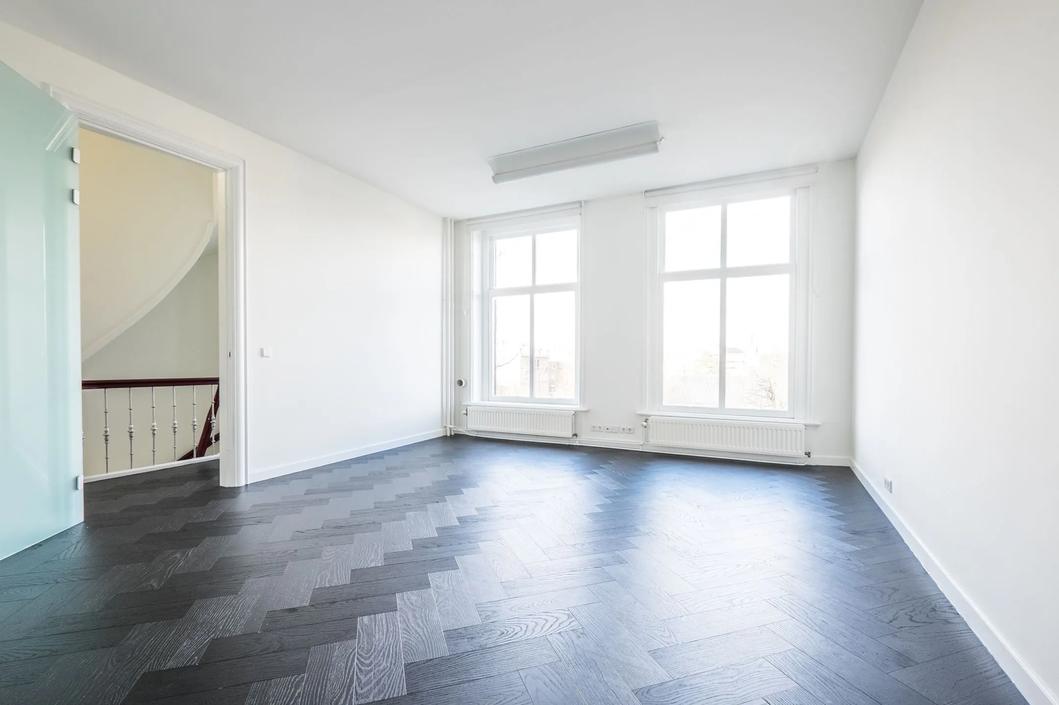 Lichte kantoorruimte aan de Sophialaan 21 in Amsterdam met visgraatvloer en grote ramen.