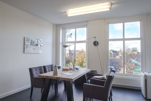 Lichte kantoorruimte aan de Sophialaan 21 in Amsterdam met grote ramen, houten vergadertafel en moderne inrichting.