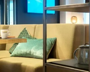 Zitgedeelte in een moderne kantoorruimte aan de Koninginnegracht in Den Haag met een beige bank, groene kussens en een koffietafel.