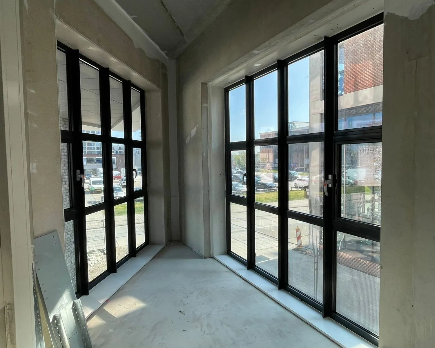 Lichte kantoorruimte in aanbouw met grote zwarte raamkozijnen aan de NDSM-Pier in Amsterdam.