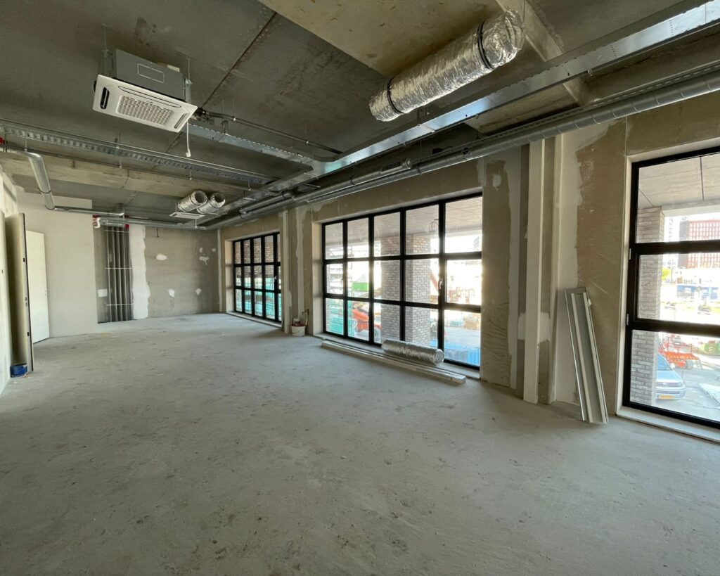 Leegstaande casco kantoorruimte met grote ramen aan de NDSM-Pier in Amsterdam.