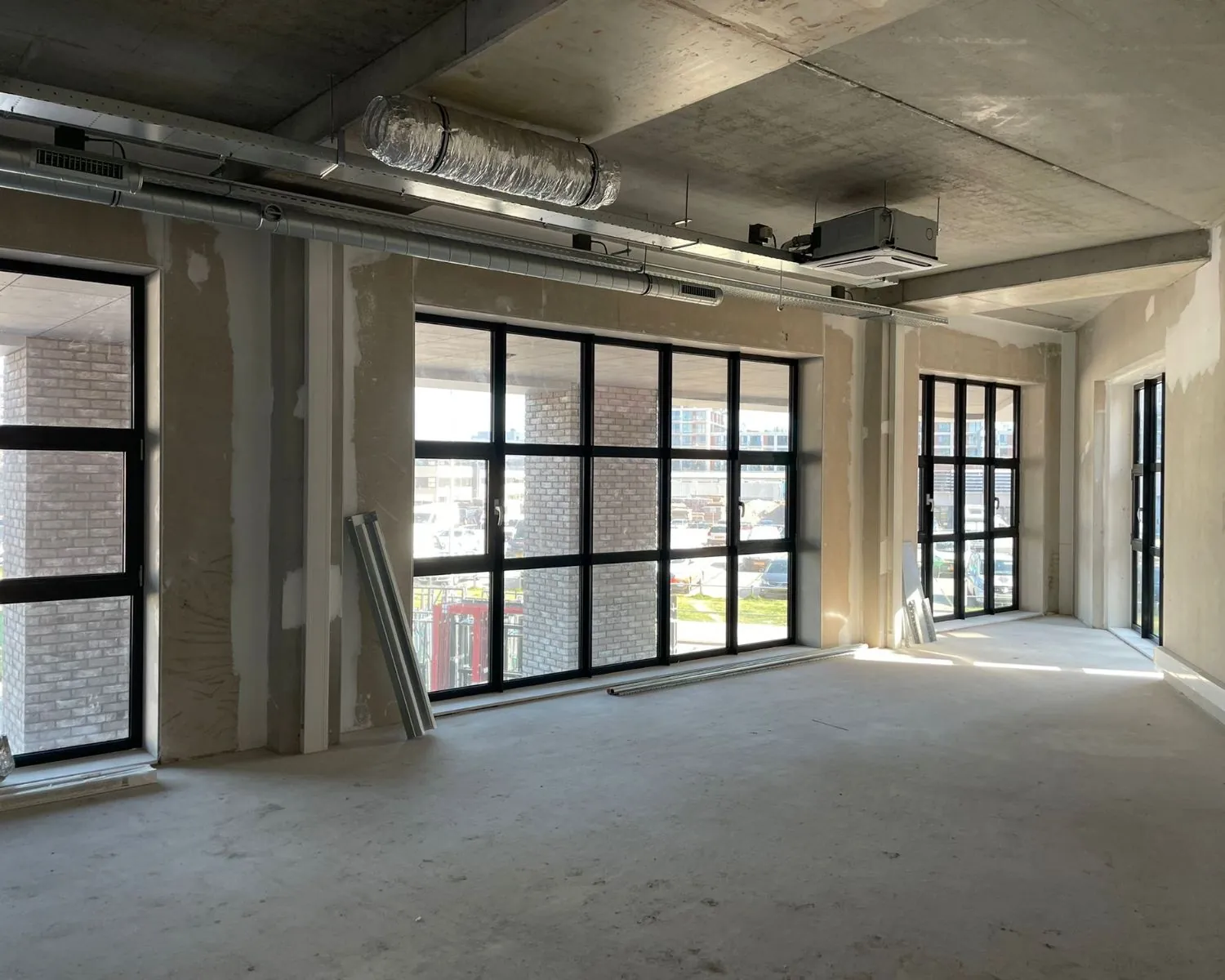 Onafgewerkte kantoorruimte met grote zwarte ramen aan de NDSM-pier in Amsterdam.