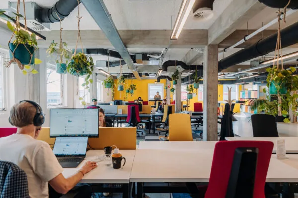 Moderne en kleurrijke kantoorruimte in Amsterdam met flexibele werkplekken en veel hangplanten.