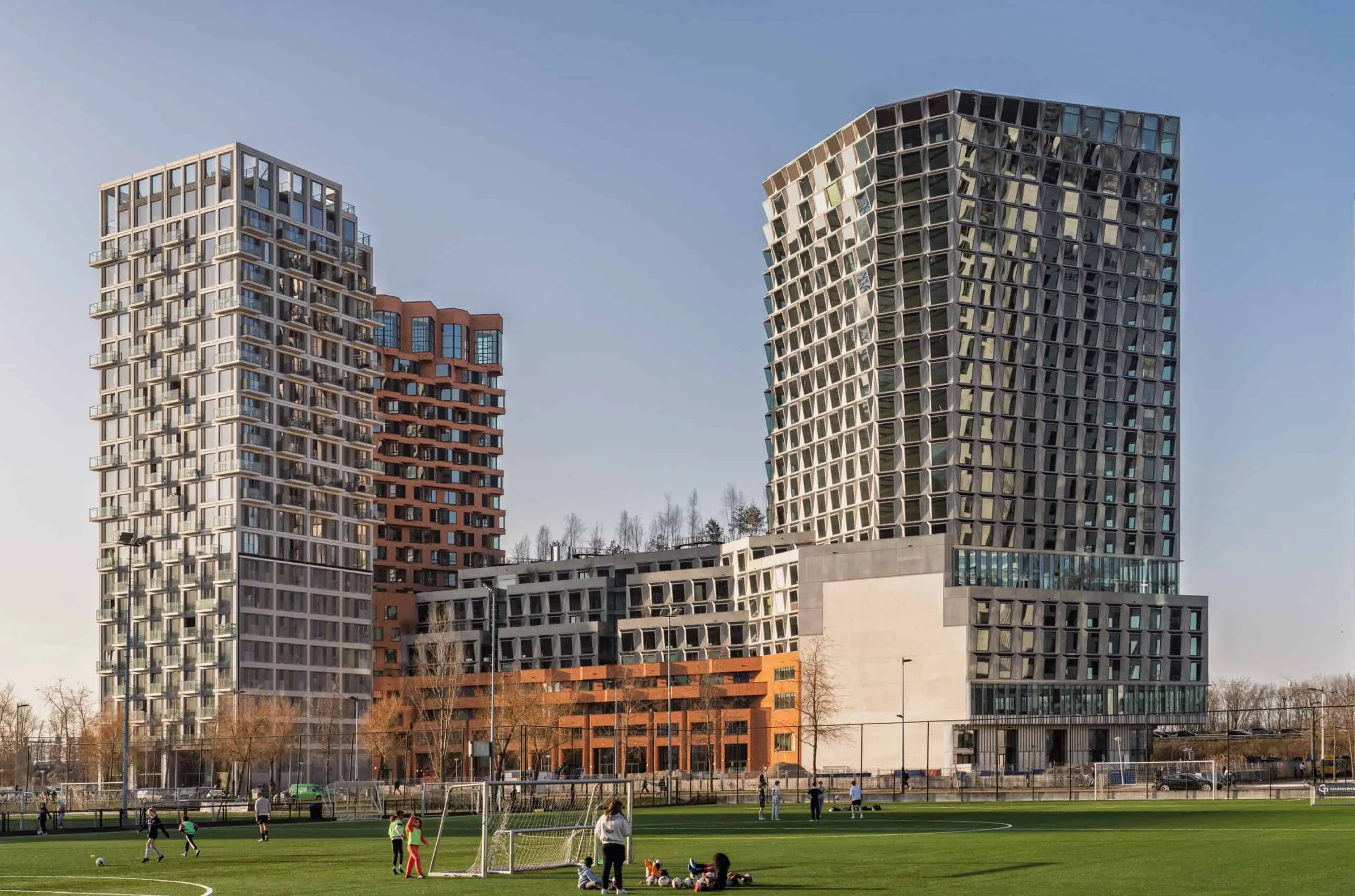 Moderne kantoorgebouwen aan de Hildegard von Bingenstraat 44 in Amsterdam met een sportveld op de voorgrond.