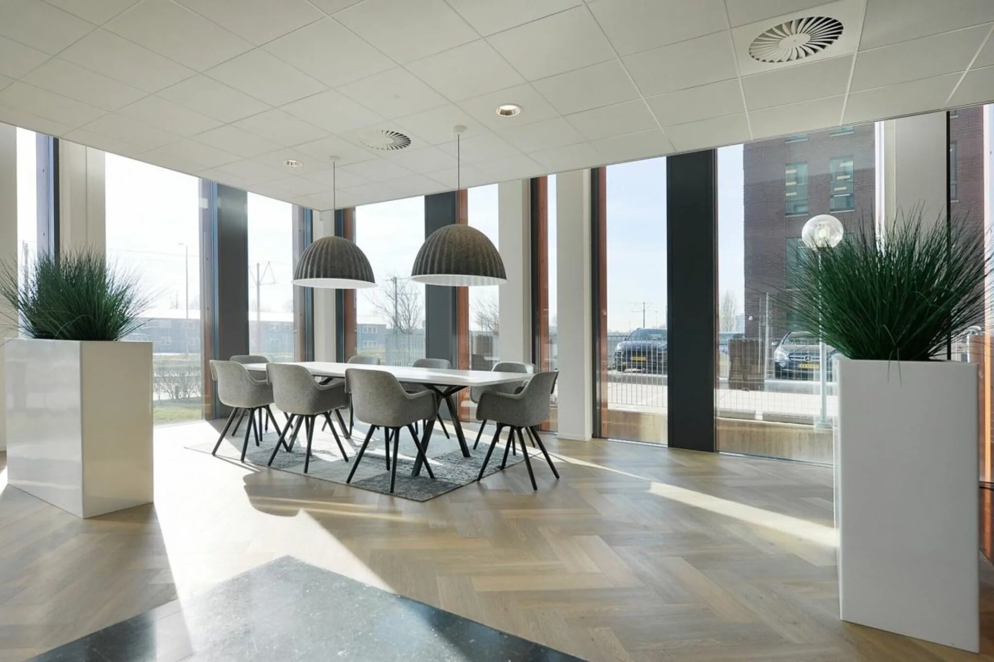 Moderne vergaderruimte in een kantoor in Rijswijk met grote ramen, designstoelen en hanglampen.