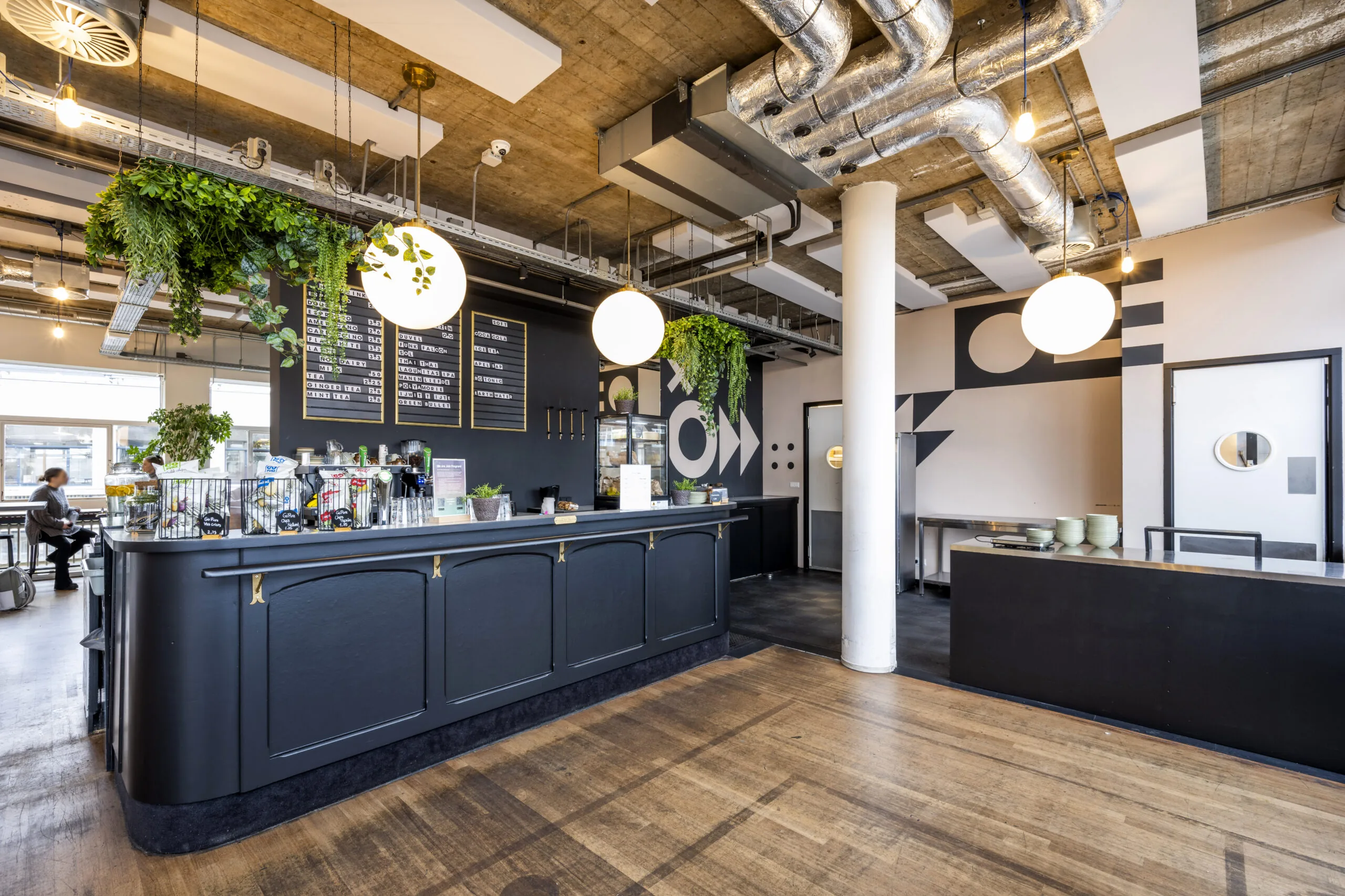 Moderne restaurant- en koffieruimte in een kantoor aan de Singel 542 in Amsterdam met industriële inrichting en veel groen.