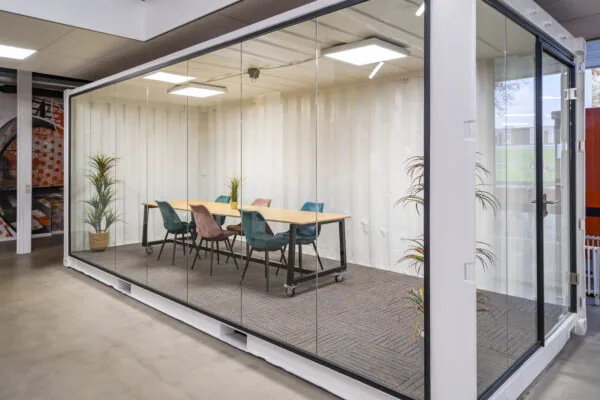 Moderne vergaderruimte met glazen wanden en kleurrijke stoelen aan de Tarasconweg 2 in Eindhoven.