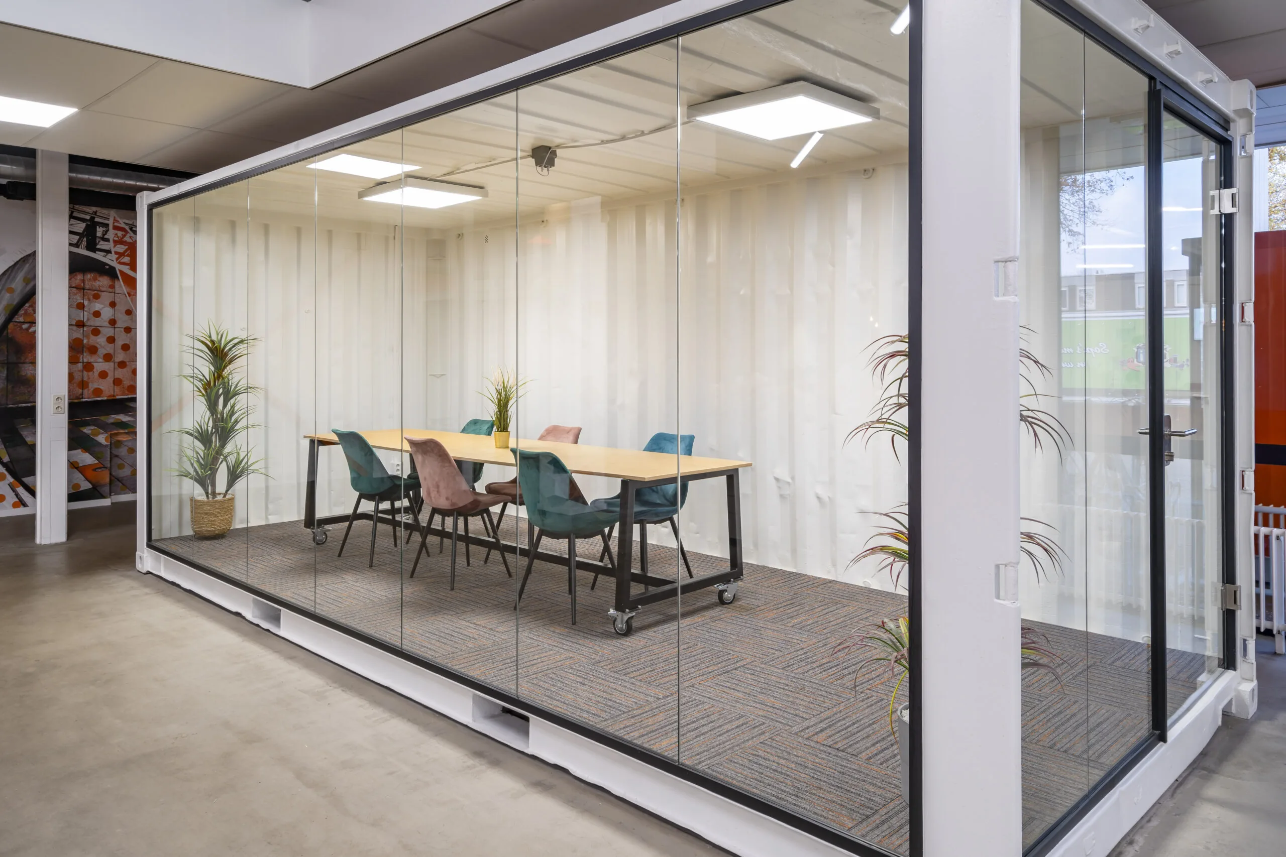Moderne vergaderruimte met glazen wanden en kleurrijke stoelen aan de Tarasconweg 2 in Eindhoven.