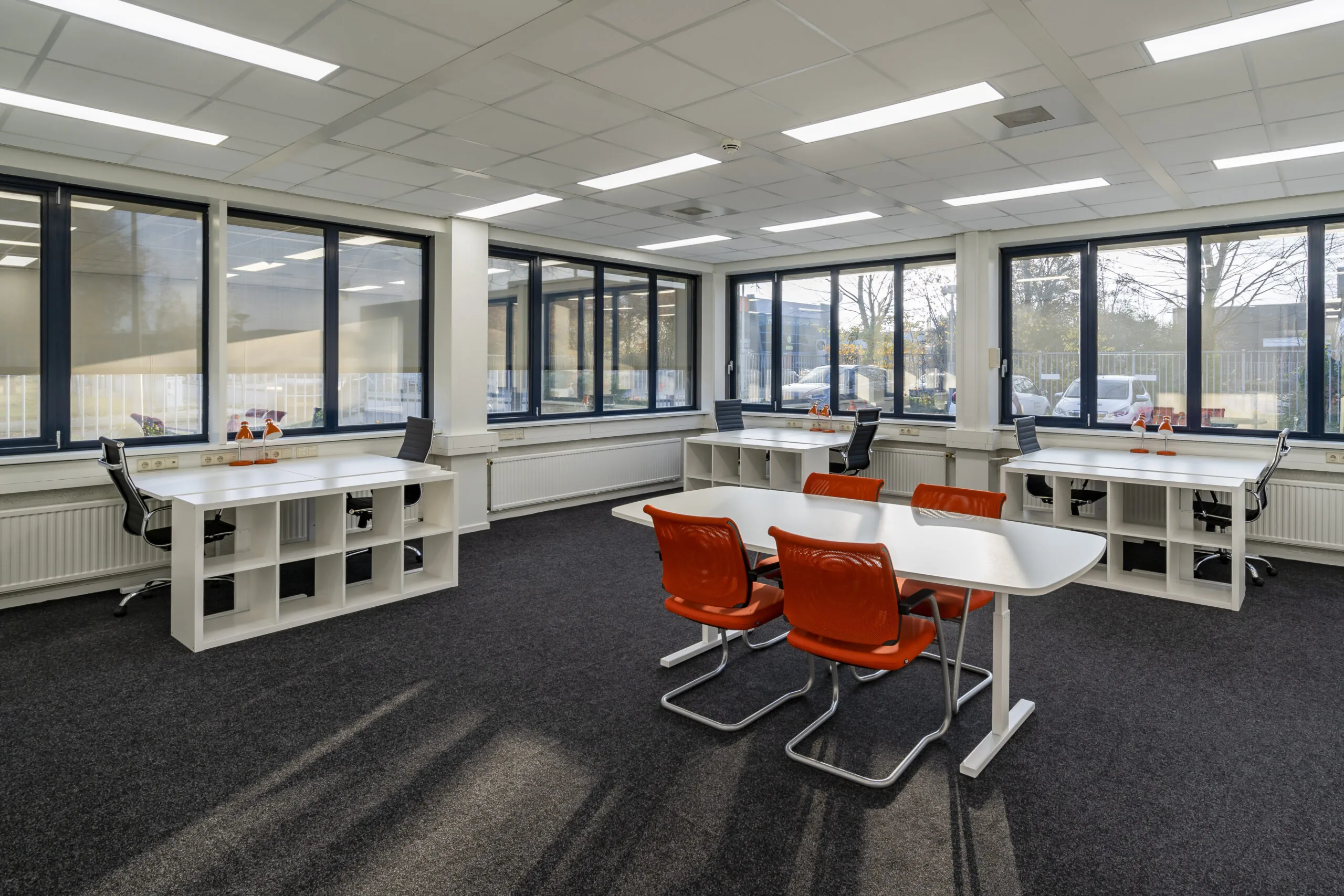 Moderne kantoorruimte aan de Tarasconweg 2 in Eindhoven met werkplekken, bureaus en oranje stoelen.