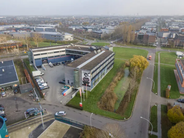 Luchtfoto van het kantoorpand aan de Transistorstraat 151 in Almere, gelegen op een bedrijventerrein met parkeergelegenheid en omliggend groen.