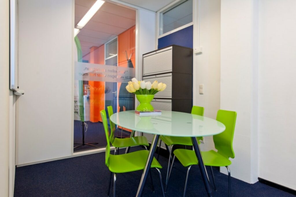 Moderne vergaderruimte in kantoor aan de Markerkant 13-70 in Almere met groene stoelen en ovale glazen tafel.