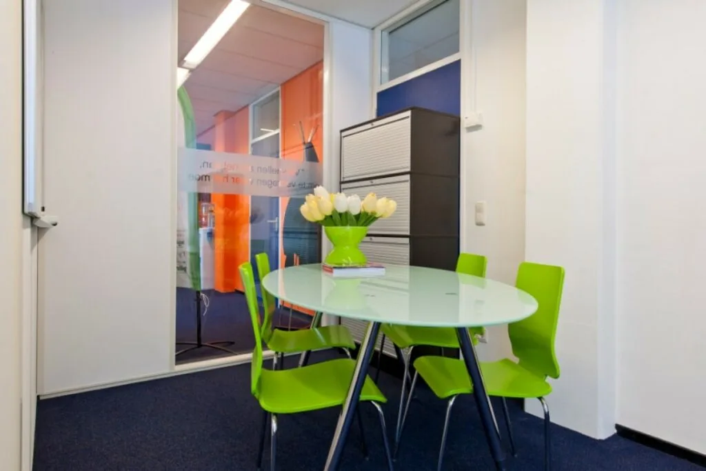 Moderne vergaderruimte in kantoor aan de Markerkant 13-70 in Almere met groene stoelen en ovale glazen tafel.