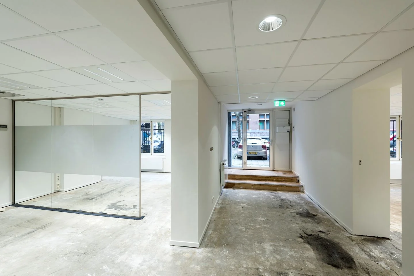 Entree van een lege kantoorruimte aan de Jan Luijkenstraat 92 in Amsterdam, met glazen scheidingswand en zicht op de straat.