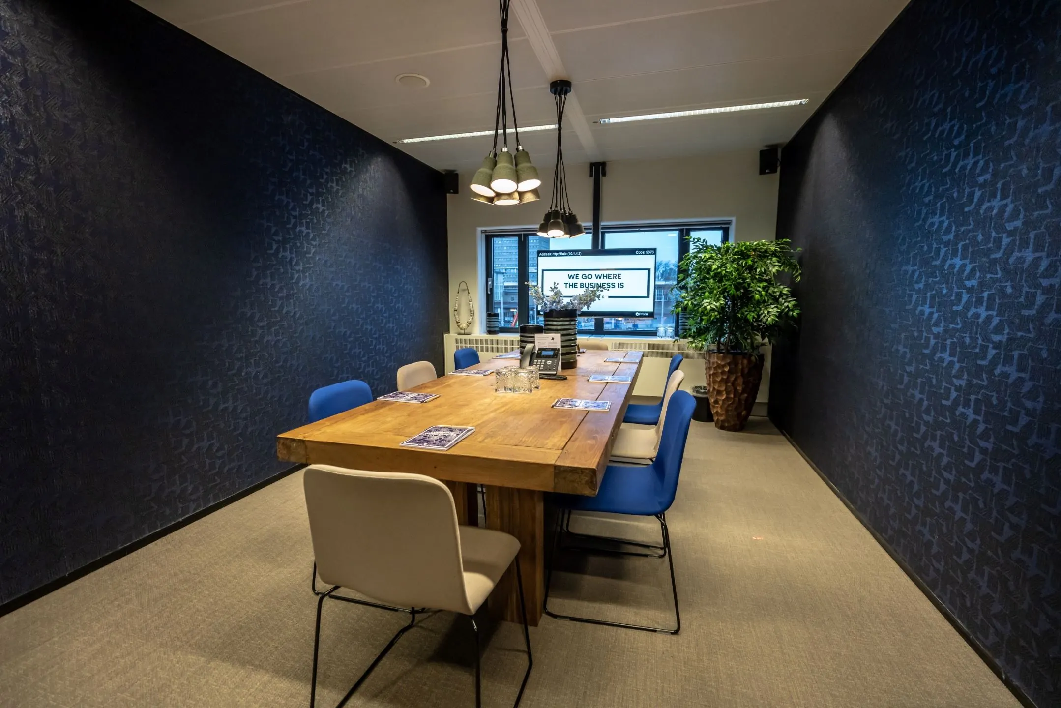 Vergaderruimte met houten tafel, moderne stoelen en presentatiescherm in een kantoor aan de Amsterdam Zuidas.