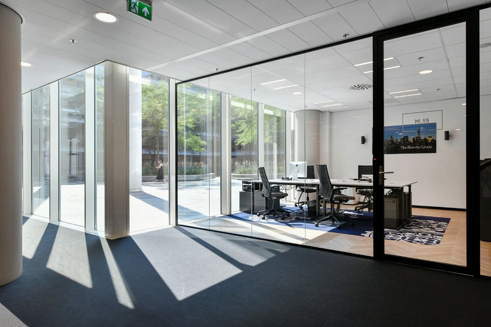 Moderne glazen kantoorruimte in Amsterdam Zuidas met werkplekken en zonlicht dat naar binnen valt.