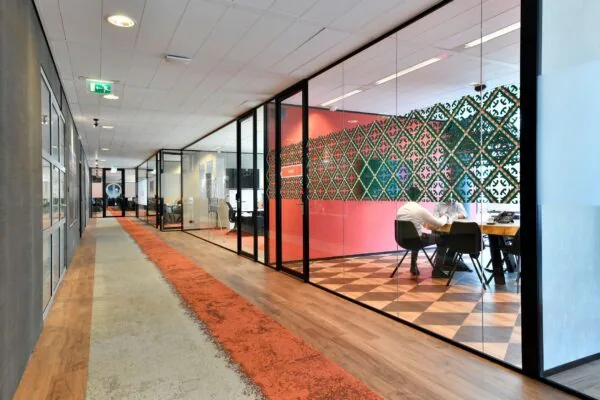 Moderne kantoorruimte aan de Zuidas in Amsterdam met glazen vergaderruimtes en kleurrijke inrichting.