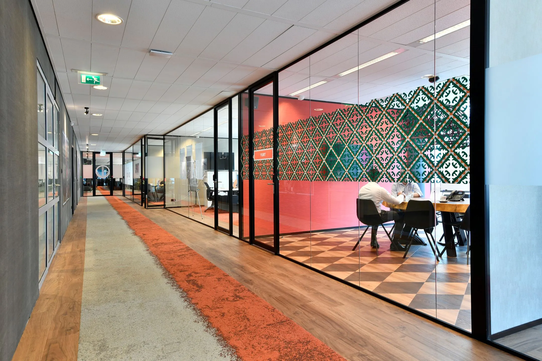 Moderne kantoorruimte aan de Zuidas in Amsterdam met glazen vergaderruimtes en kleurrijke inrichting.