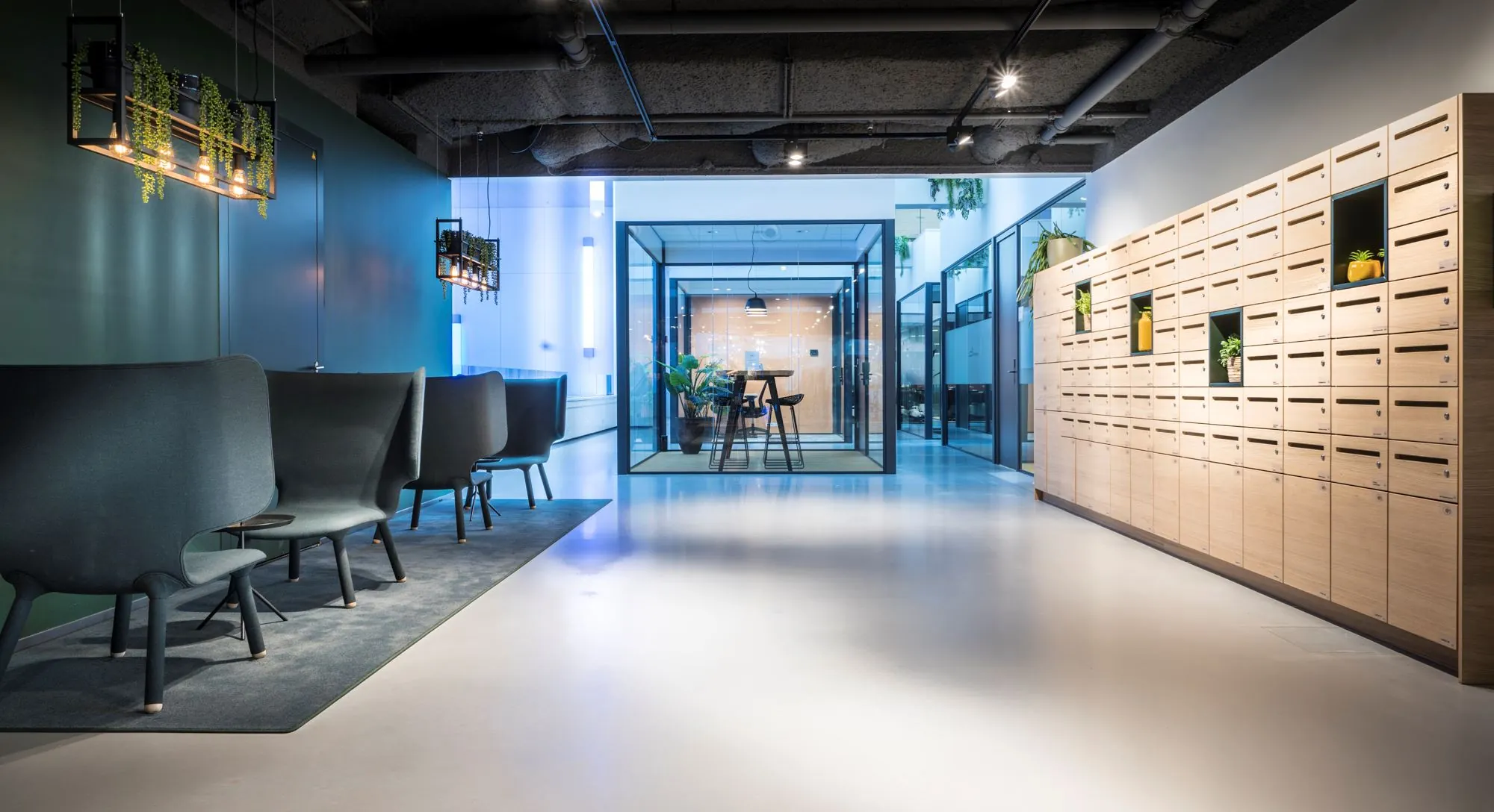 Moderne kantoorruimte aan de Bargelaan 200 in Leiden met designmeubilair, glazen vergaderruimtes en een wand met houten postvakken.