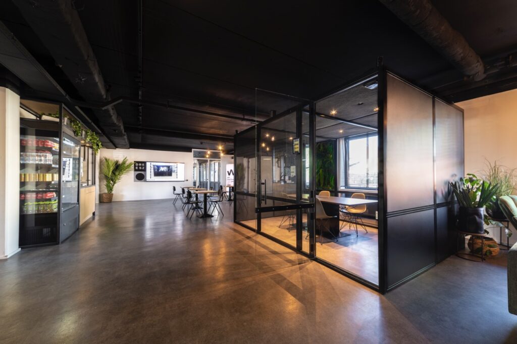 Moderne kantoorruimte aan de Brugstraat 11 in Almelo met glazen vergaderruimte, zithoeken en een gekoelde drankautomaat.