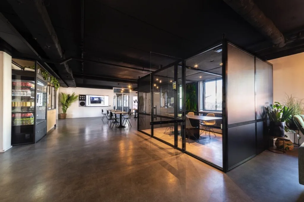 Moderne kantoorruimte aan de Brugstraat 11 in Almelo met glazen vergaderruimte, zithoeken en een gekoelde drankautomaat.