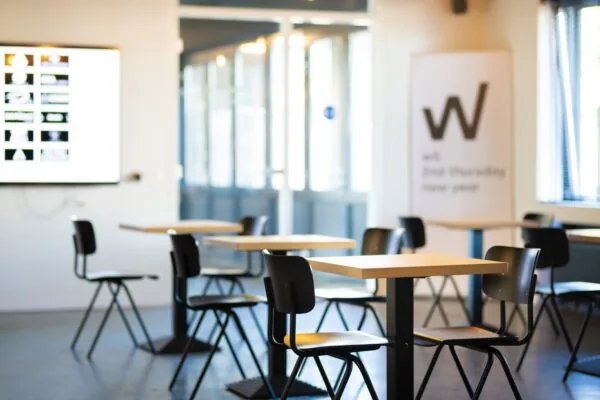 Moderne, lichte kantoorruimte aan de Brugstraat 11 in Almelo met tafels, stoelen en een presentatiescherm.