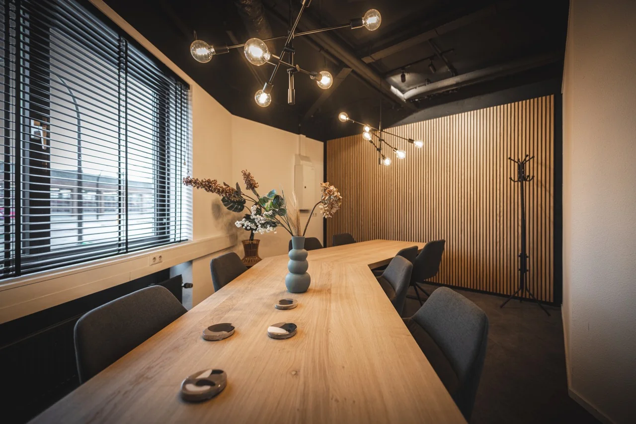 Moderne vergaderruimte aan de Brugstraat 11 in Almelo met houten tafel, designverlichting en houten lattenwand.