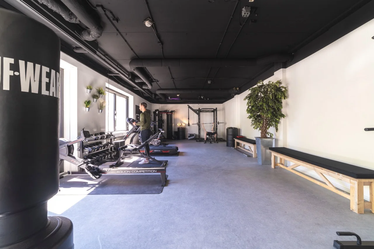 Moderne fitnessruimte in kantoor aan de Brugstraat 11 in Almelo met fitnessapparatuur, bokszak en een persoon op een loopband.