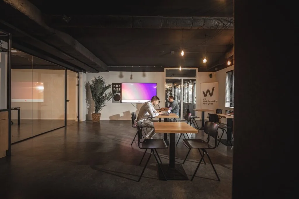 Moderne kantoorruimte aan de Brugstraat 11 in Almelo met twee personen werkend aan een tafel in een open, sfeervol ingerichte ruimte.