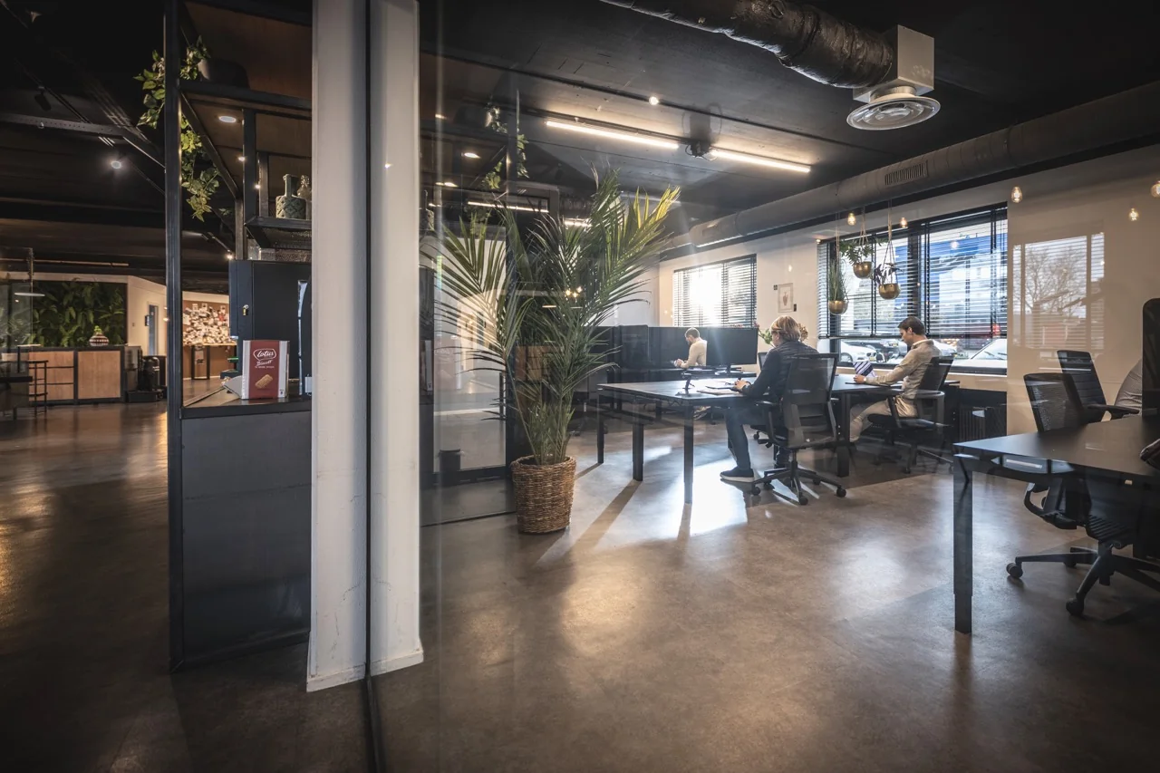 Moderne kantoorruimte aan de Brugstraat 11 in Almelo met werkplekken, glazen wanden en industriële inrichting.