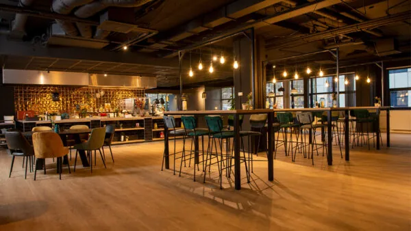 Moderne gemeenschappelijke kantoorruimte aan de Bruistensingel 400 in Den Bosch met hoge tafels, barzitjes en warme sfeerverlichting.