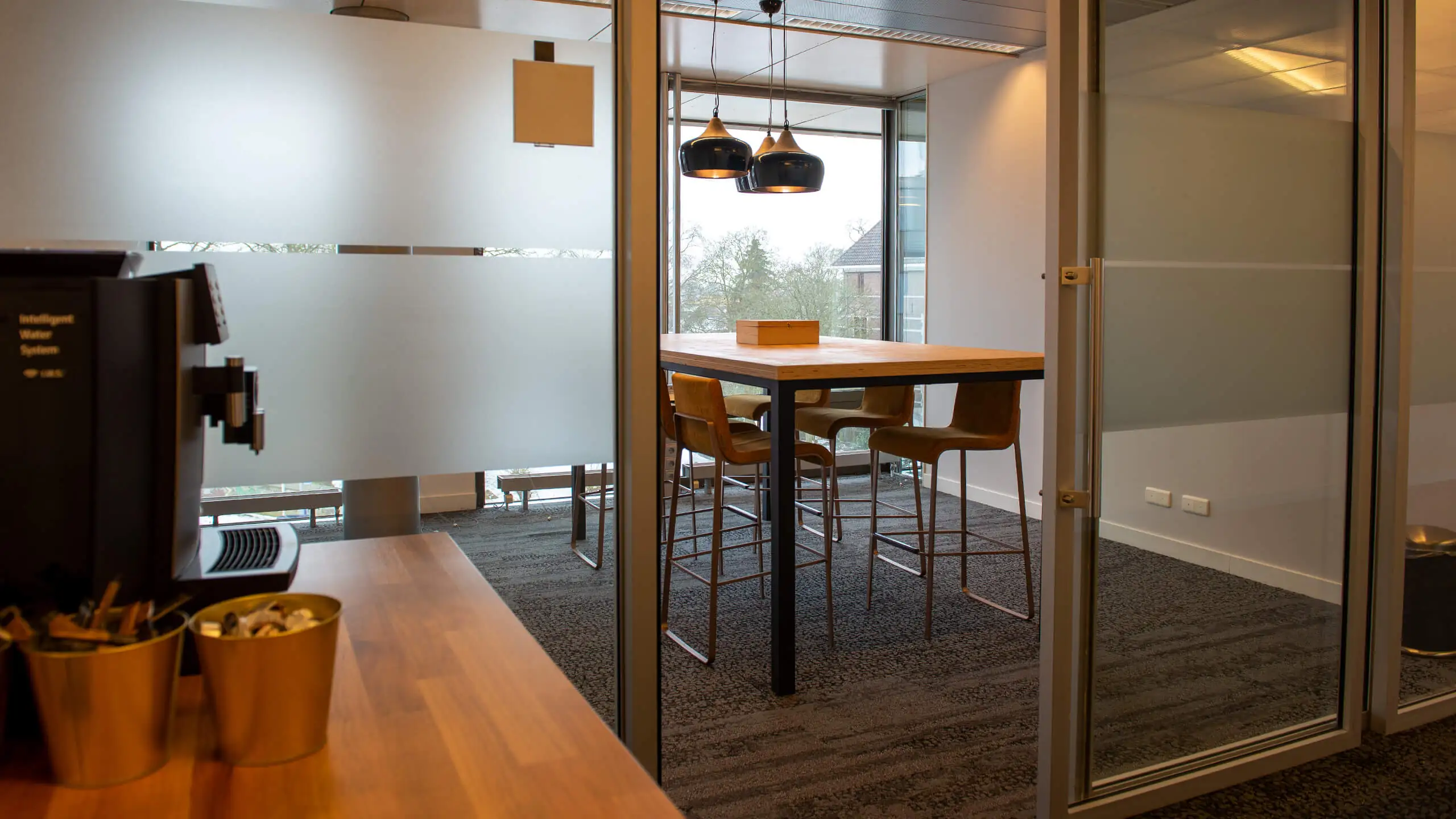 Moderne vergaderruimte aan de Bruistensingel 400 in Den Bosch met hoge tafel, barkrukken en hanglampen.