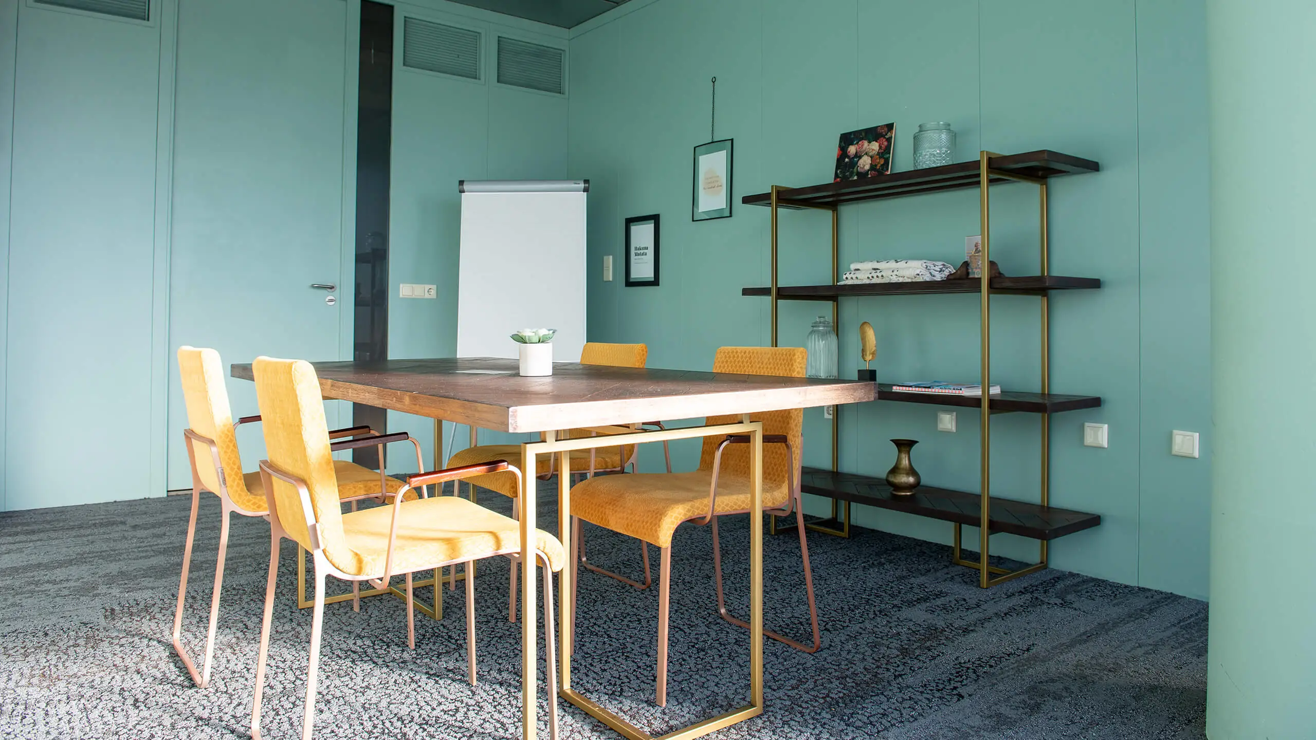 Moderne vergaderruimte met gele stoelen, houten tafel en open wandrek aan de Bruistensingel 400 in Den Bosch.