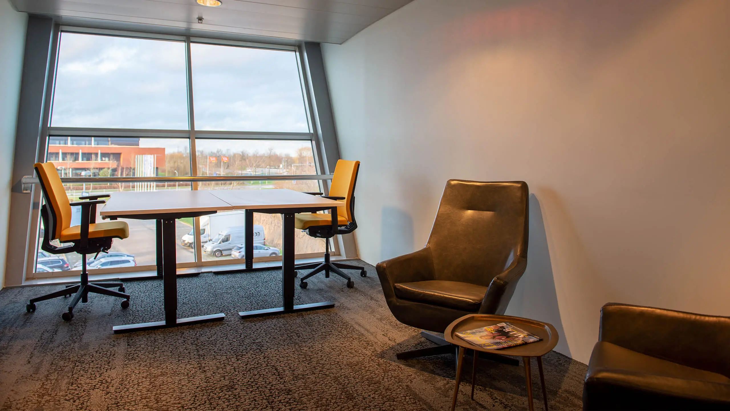 Moderne kantoorruimte aan de Bruistensingel 400 in Den Bosch met grote ramen, twee bureaustoelen en een zithoek.