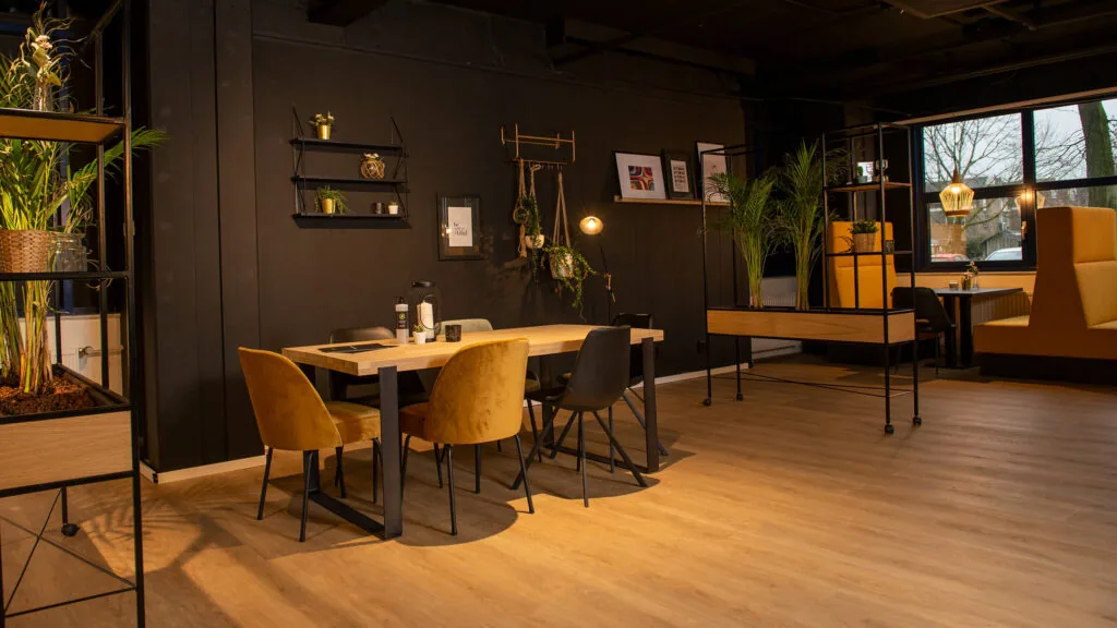 Moderne en sfeervolle kantoorruimte aan de Bruistensingel 400 in Den Bosch met houten vloer, zwarte wanden en geel gestoffeerde zitplekken.