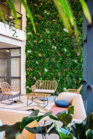 Moderne kantoorlounge aan de Bruistensingel 500 in Den Bosch met rotan zitmeubels en een groene plantenwand.