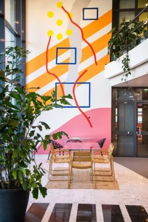 Moderne kantoorruimte aan de Bruistensingel 500 in Den Bosch met kleurrijke wandkunst, glazen vergadertafel en omringend groen.