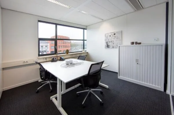 Moderne kantoorruimte met twee bureaus en uitzicht op het rode kantoorgebouw aan de Ceresstraat 1 in Breda.