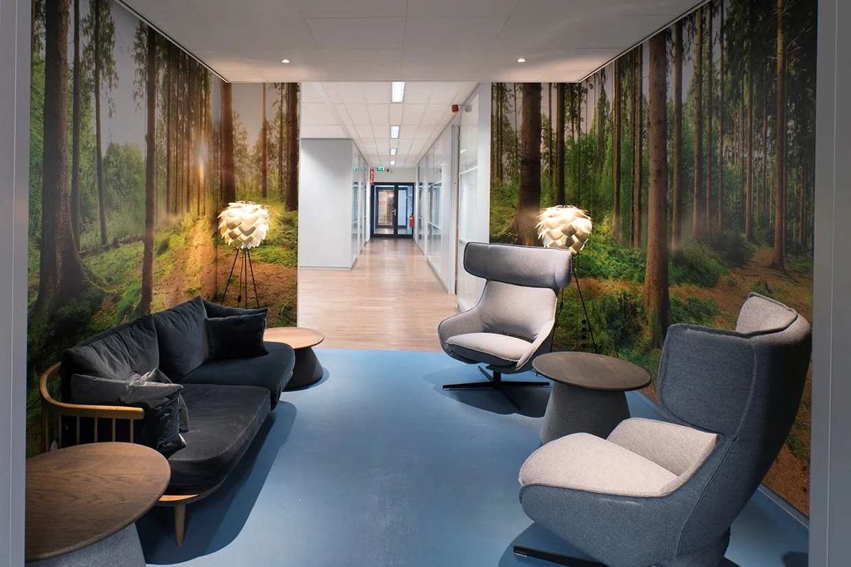 Moderne wachtruimte in kantoorruimte aan Handelsplein 59 in Amstelveen met comfortabele zitmeubels en een wandprint van een bos.
