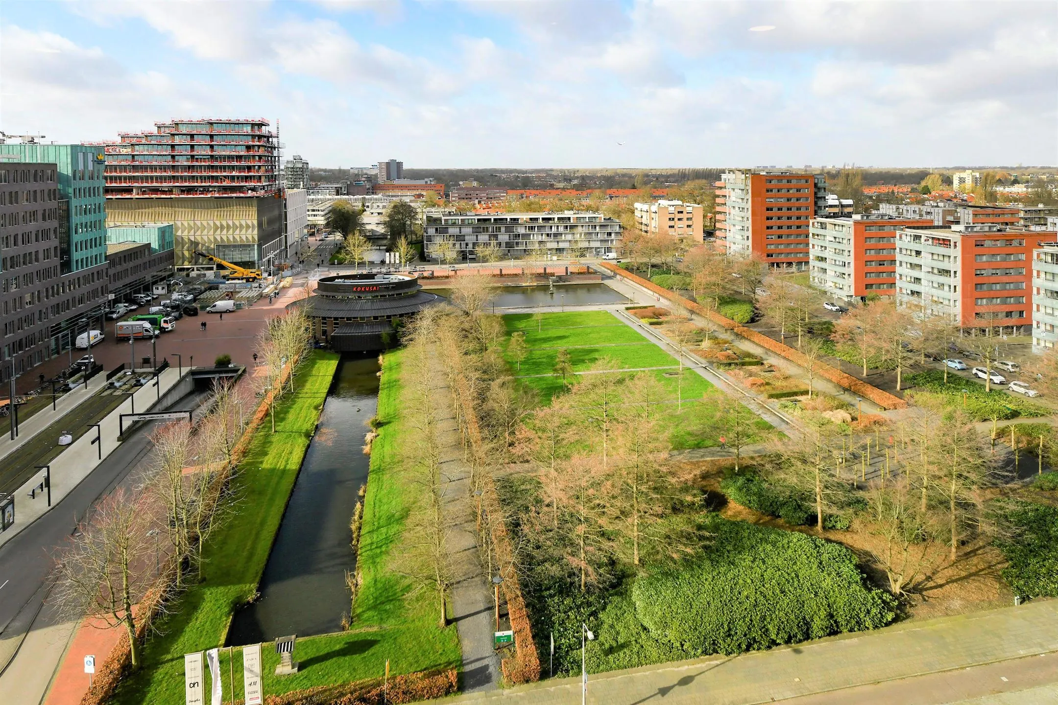 Luchtfoto van Handelsweg 59 in Amstelveen met kantoren, woontorens en een groen park met waterpartij.