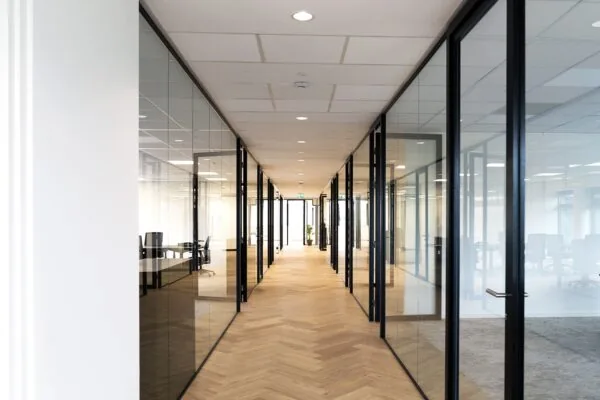 Lichte, moderne kantoorruimte in Hoofddorp met glazen wanden en houten visgraatvloer.