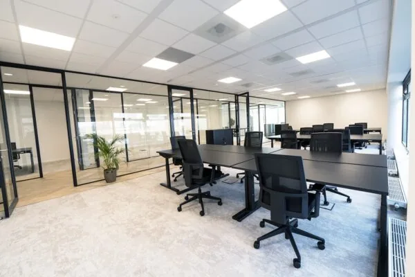 Moderne kantoorruimte in Hoofddorp met glazen vergaderruimtes en zwarte bureaustoelen.
